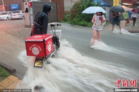2012年7月21日，北京普降暴雨，朝阳区北部立水桥南地区积水严重。一小区门口，积水沿斜坡形成巨大水流，阻碍人们通行。图片来源：CFP视觉中国