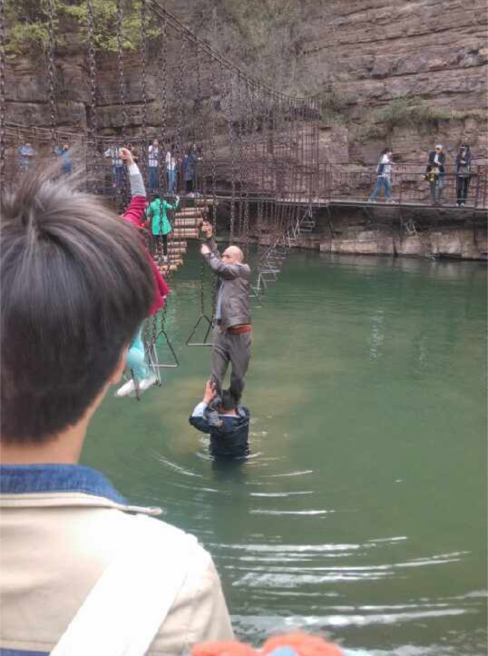 洛阳龙潭峡景区工作人员让游客踩肩过河