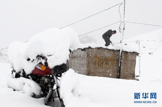 新疆哈密突降大雪 草原上的牧民在清理屋顶积雪