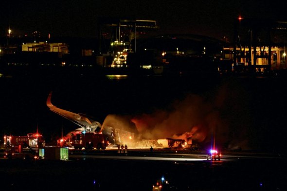 2024年1月2日，日本东京羽田国际机场，消防队员在一架燃烧的日本航空A350飞机上工作。