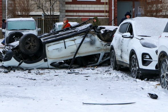 2024年1月5日，乌克兰袭击俄罗斯别尔哥罗德市，人们站在多层公寓楼庭院里受损的汽车旁边。